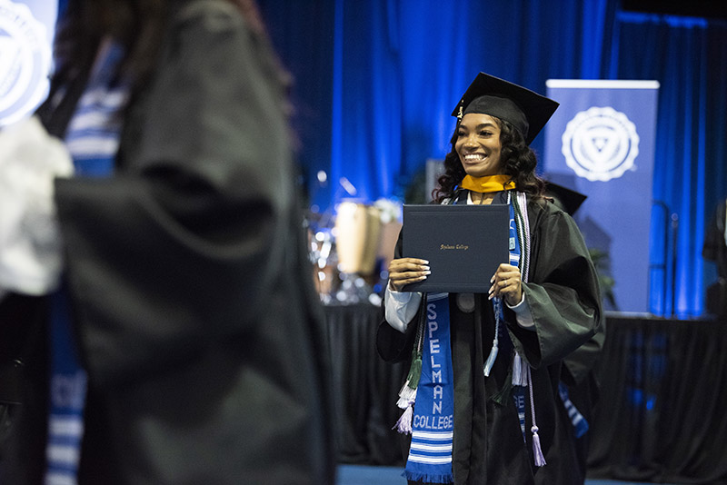 Spelman College Commencement 2023 - Graduate holding diploma on stage.