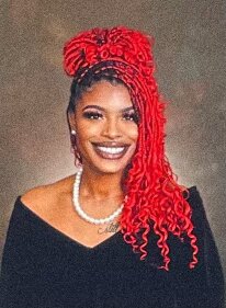 Peyton Shemaiah smiling with her graduation dress on, with her red locs styled in an up and down style.