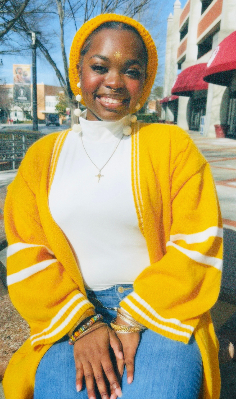 Asiana Belcher smiling, wearing a yellow outfit.